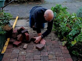 Man is de voortuin aan het bestraten met roze klinkers