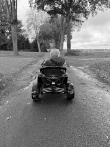 Zwart wit foto van dreumes op elektrische auto op de weg