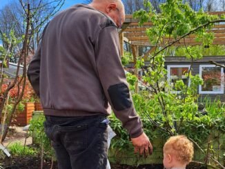 Opa en kleinzoon voor een verticale kruidentoren in de tuin